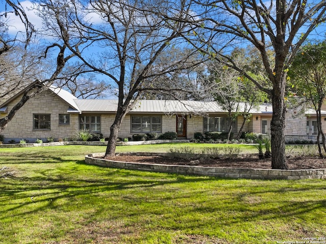 ranch-style home with metal roof, stone siding, and a front yard