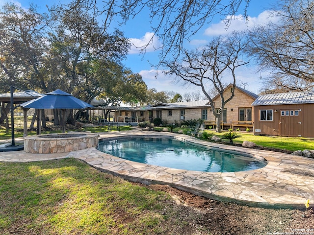 pool featuring an in ground hot tub, a lawn, an outbuilding, and a patio