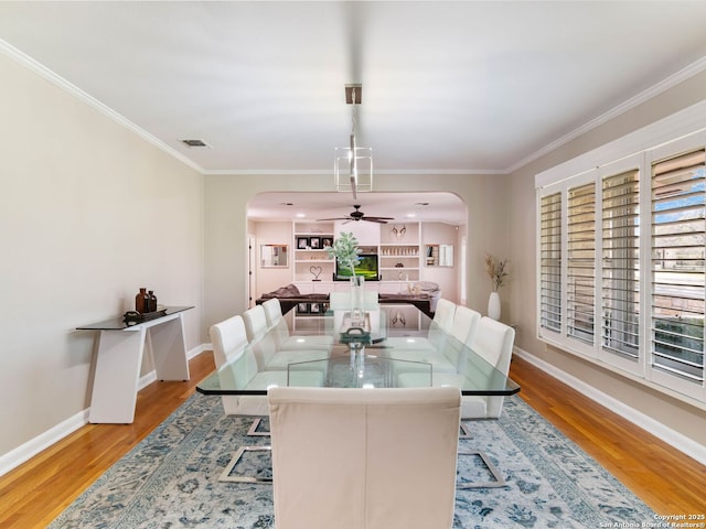 dining room featuring wood finished floors, baseboards, visible vents, arched walkways, and ornamental molding