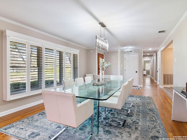 dining space featuring crown molding, baseboards, visible vents, and light wood finished floors