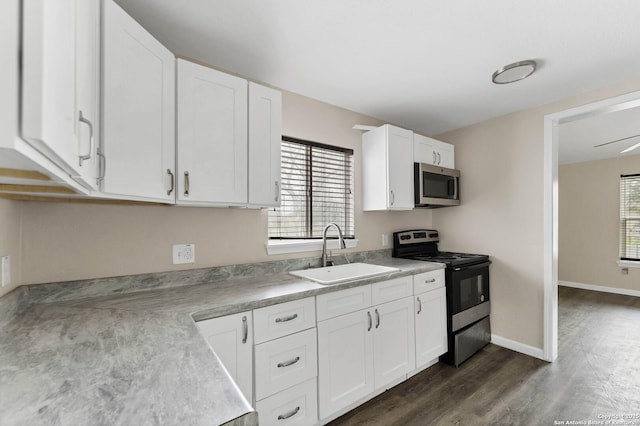 kitchen featuring stainless steel appliances, light countertops, dark wood-type flooring, white cabinetry, and a sink