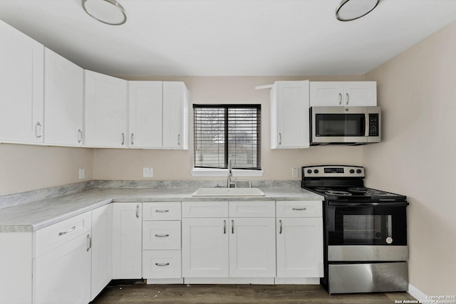 kitchen with light countertops, appliances with stainless steel finishes, a sink, and white cabinets