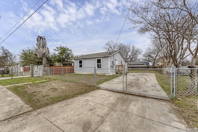 view of side of home featuring a fenced front yard, a gate, a lawn, and concrete driveway