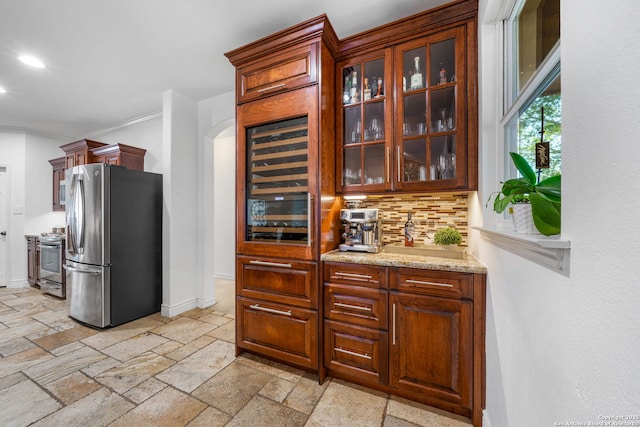 kitchen with baseboards, appliances with stainless steel finishes, decorative backsplash, and stone tile flooring