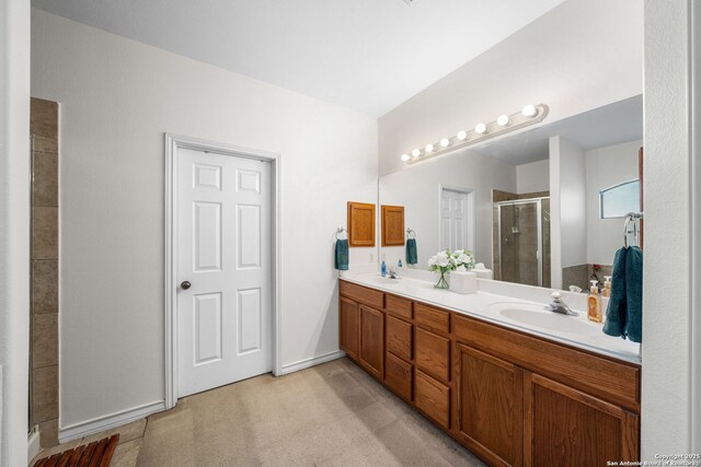 bathroom featuring double vanity, a stall shower, and a sink