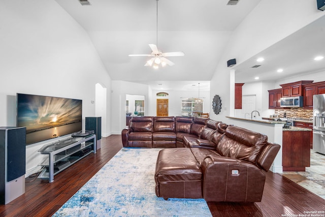 living area featuring ceiling fan, arched walkways, dark wood finished floors, and visible vents