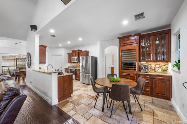 kitchen featuring arched walkways, visible vents, appliances with stainless steel finishes, a peninsula, and baseboards