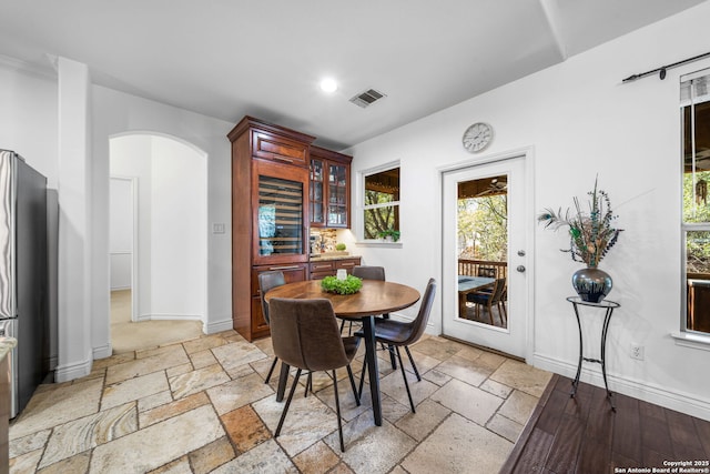 dining area featuring baseboards, visible vents, arched walkways, stone tile flooring, and recessed lighting