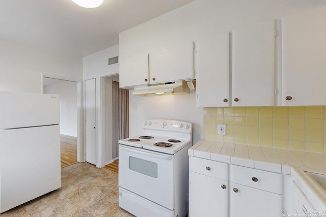 kitchen with tile counters, tasteful backsplash, white cabinets, white appliances, and under cabinet range hood