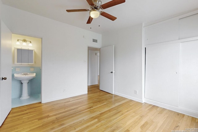 unfurnished bedroom featuring ensuite bathroom, wood finished floors, and visible vents