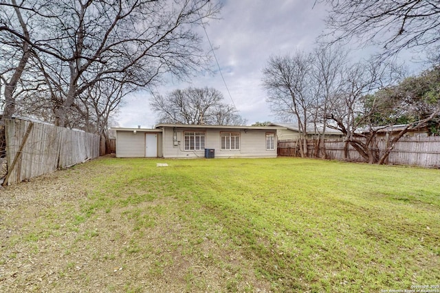 rear view of property with central AC, a lawn, and a fenced backyard