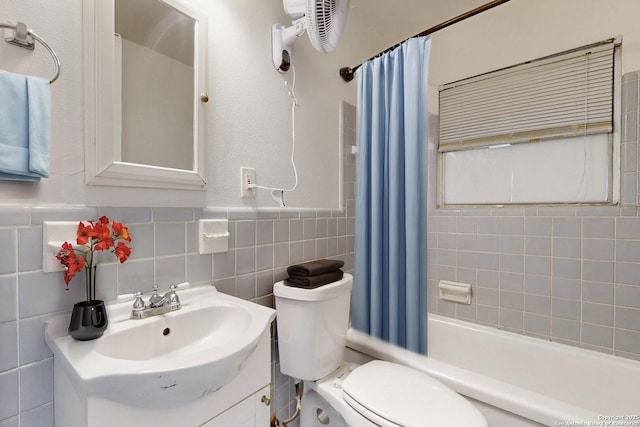 full bath with a wainscoted wall, tile walls, shower / bathtub combination with curtain, toilet, and vanity