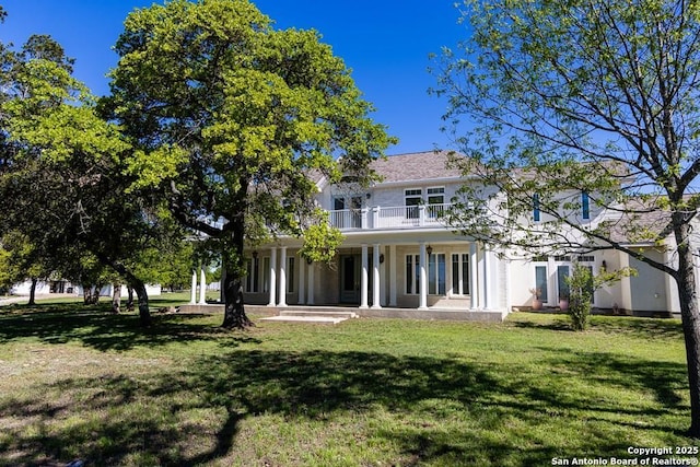 rear view of property with a balcony and a yard