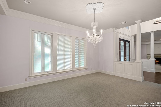 unfurnished room with carpet floors, crown molding, a lit fireplace, and ornate columns