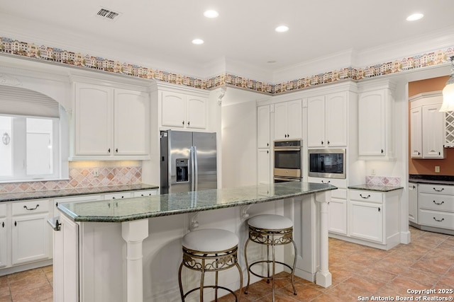 kitchen featuring appliances with stainless steel finishes, decorative backsplash, a center island, and white cabinets