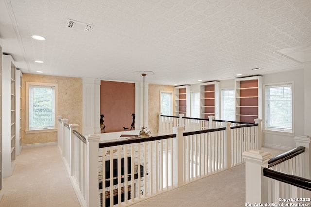 hall featuring baseboards, visible vents, carpet flooring, and an upstairs landing