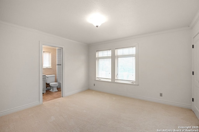 unfurnished bedroom featuring ornamental molding, light colored carpet, baseboards, and ensuite bathroom