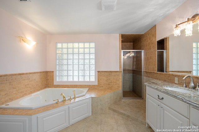 bathroom with a bath, tile patterned floors, vanity, a shower stall, and tile walls