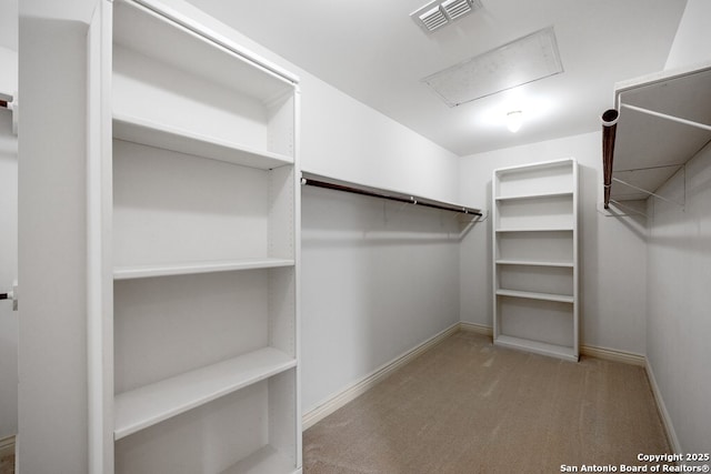 spacious closet with carpet floors, visible vents, and attic access