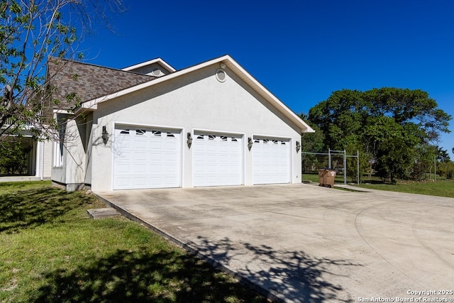 view of side of property with concrete driveway, roof with shingles, an attached garage, a yard, and stucco siding