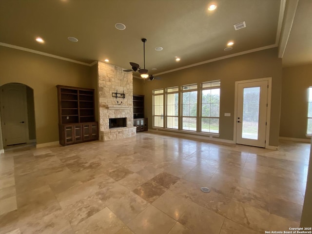 unfurnished living room featuring arched walkways, a fireplace, visible vents, a ceiling fan, and baseboards