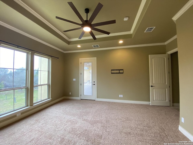 unfurnished room featuring carpet floors, visible vents, a raised ceiling, and ornamental molding