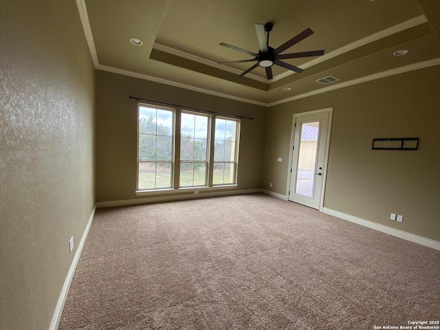 carpeted empty room with baseboards, a tray ceiling, visible vents, and crown molding