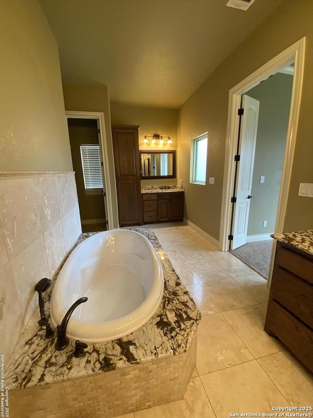 bathroom featuring a garden tub, visible vents, baseboards, vanity, and tile patterned floors