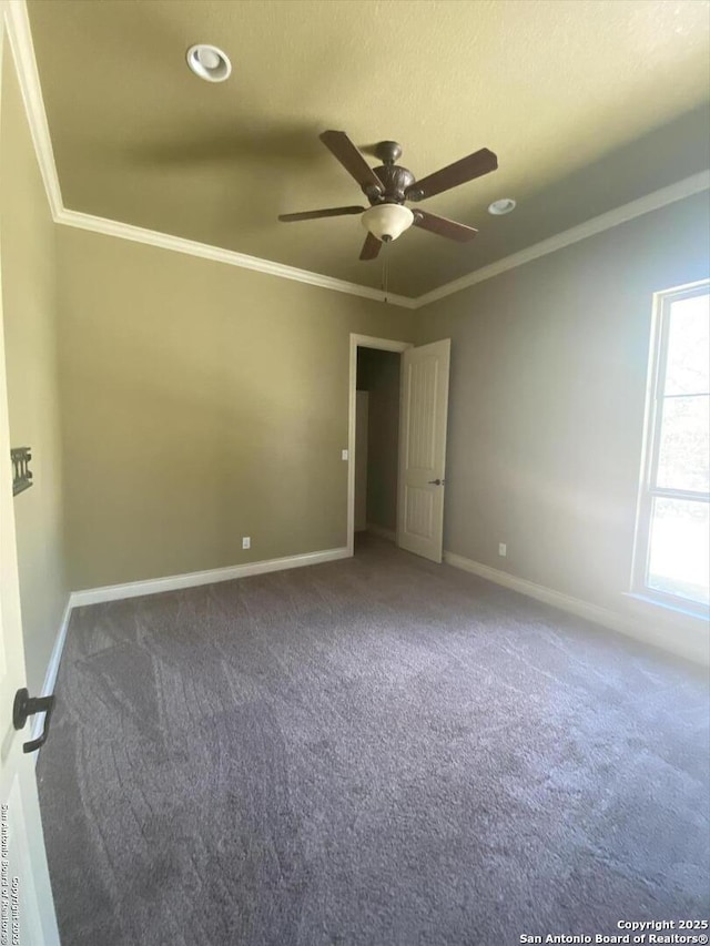 carpeted spare room featuring a ceiling fan, baseboards, and crown molding