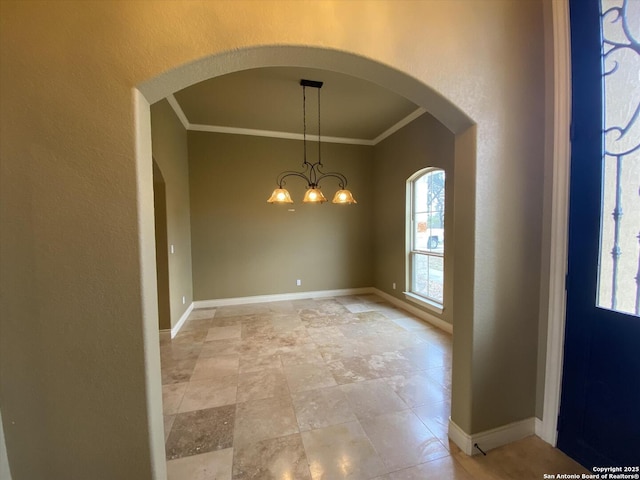 interior space with baseboards, a chandelier, and crown molding