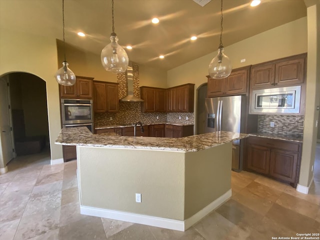 kitchen featuring light stone countertops, a spacious island, wall chimney exhaust hood, and arched walkways