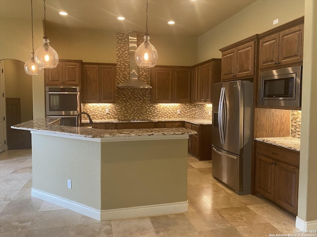 kitchen featuring wall chimney range hood, stone countertops, arched walkways, and stainless steel appliances