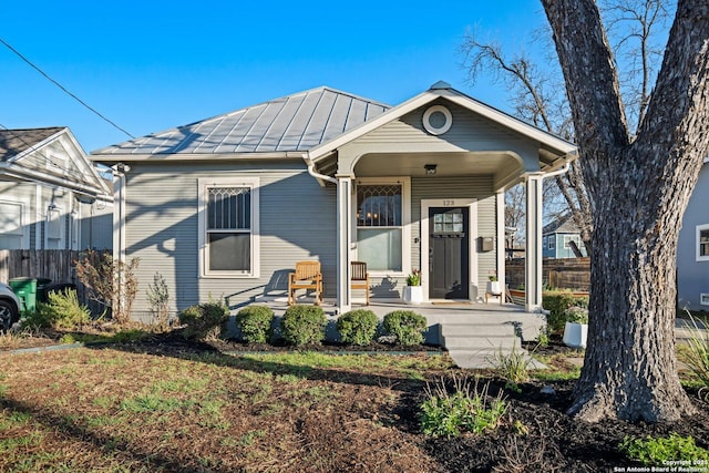 view of front of home featuring a porch, metal roof, a standing seam roof, and fence