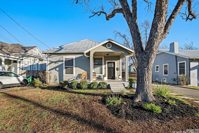 bungalow with a chimney, a porch, metal roof, and fence