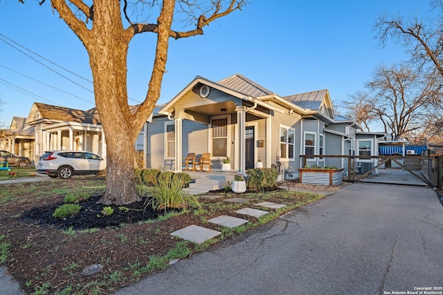 view of front of property with a standing seam roof, a gate, fence, covered porch, and metal roof