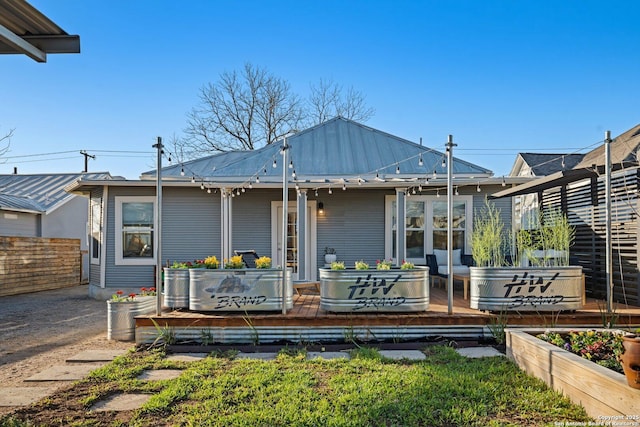 back of property featuring a standing seam roof, fence, and metal roof