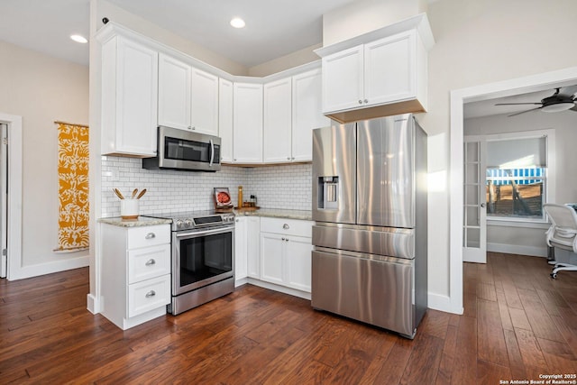 kitchen with tasteful backsplash, dark wood-type flooring, light stone countertops, appliances with stainless steel finishes, and white cabinets