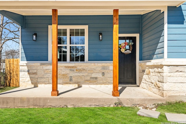 view of exterior entry with stone siding and a porch