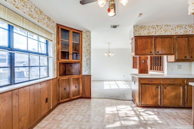 kitchen with ceiling fan with notable chandelier, visible vents, light countertops, brown cabinets, and light floors