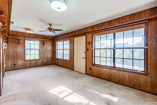 interior space with wood walls, ceiling fan, and baseboards