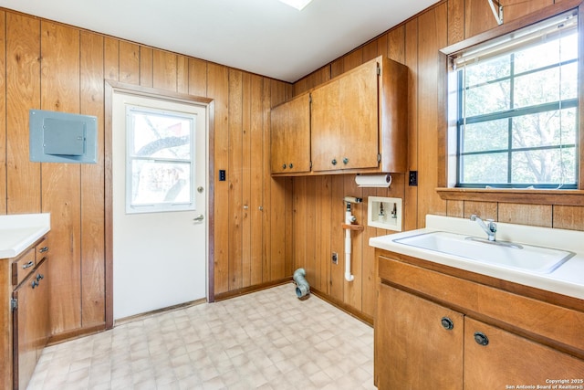 washroom featuring wooden walls, washer hookup, a sink, cabinet space, and light floors