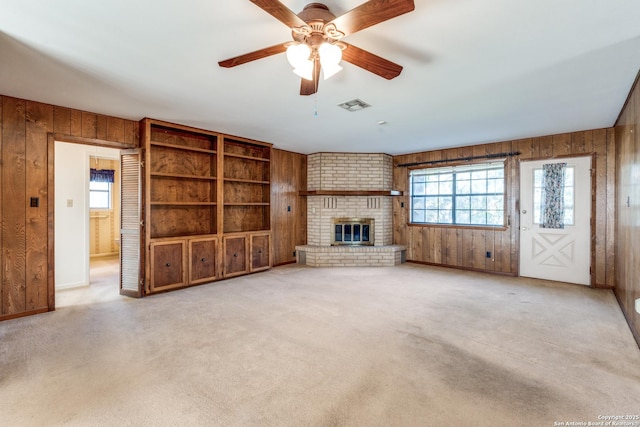 unfurnished living room with carpet floors, wood walls, and a wealth of natural light