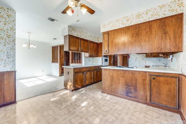 kitchen with wall oven, brown cabinetry, a peninsula, and light floors