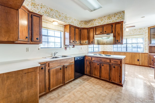 kitchen with brown cabinets, wainscoting, dishwasher, under cabinet range hood, and wallpapered walls