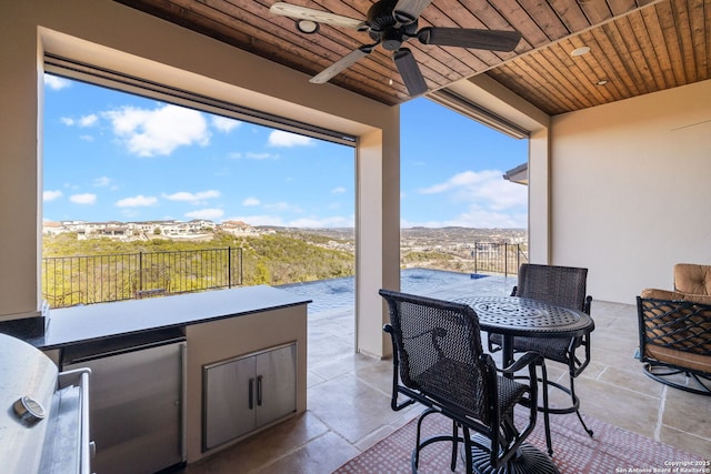 view of patio / terrace featuring exterior kitchen, outdoor dining area, fence, and a ceiling fan