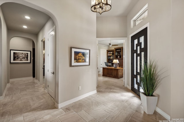 entrance foyer featuring baseboards, arched walkways, a chandelier, and recessed lighting