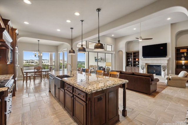 kitchen with stone tile floors, a premium fireplace, a sink, stainless steel dishwasher, and a kitchen bar