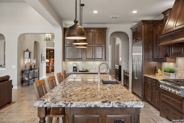 kitchen with light stone countertops, visible vents, appliances with stainless steel finishes, and a sink