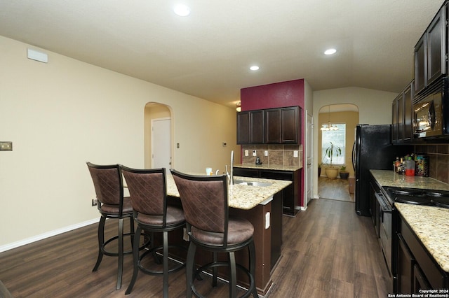 kitchen with arched walkways, lofted ceiling, a sink, black appliances, and dark wood finished floors