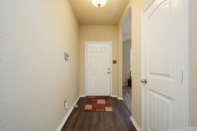 hall featuring baseboards, arched walkways, and wood finished floors